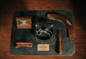 Hat sizing tool placed next to a set of wooden hat blocks and brim flanges, used in traditional hatmaking.